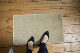 Worn texture of distressed Oushak rug mat with pale ivory and beige open field.