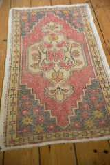 Intricate floral motifs in faded red, ivory, and grey on a distressed Oushak rug corner.