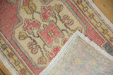 Vintage distressed Oushak rug, folded to reveal faded blush pile, hand-knotted reverse, and fringe.