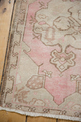Vintage Oushak rug corner close-up, pink and ivory floral spandrel with distressed pile.