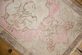 Distressed Oushak rug texture with soft pink, ivory, and beige floral elements at the corner.