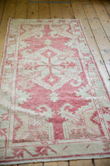 Distressed Oushak runner corner, faded cochineal red, antique ivory, serrated leaves.