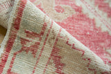 Close-up of distressed Oushak rug pile texture, with faded red and antique ivory.