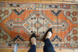 Distressed Turkish Oushak rug runner with central diamond medallion, faded rust, ivory, and charcoal.