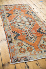 Distressed Oushak runner end, showing faded orange-red pile, secured edge, and fringe.