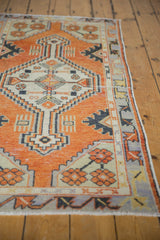 Distressed Oushak runner's geometric medallion in faded rust, ivory, and charcoal with worn texture.