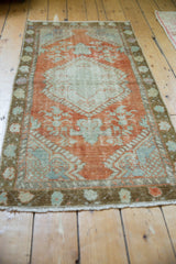 Distressed vintage Oushak runner, showing faded rust and pale mint floral designs with worn pile.