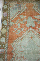 Distressed Oushak runner with pale rust and mint patterns and faint foundation showing.