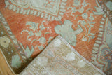 Distressed Oushak rug's pale rust pile showing faint foundation, hand-knotted back, and fringe.