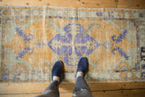 Distressed vintage Oushak runner with golden, royal blue, seafoam colors, and visible texture.