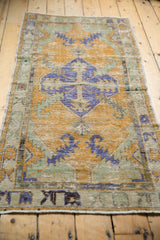 Distressed vintage Oushak runner close-up, showing worn royal blue, dusty gold, seafoam green patterns.