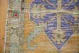 Distressed Oushak rug corner featuring texture in dusty gold, royal blue, seafoam green, and ivory.