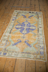 Distressed royal blue diamond medallion and sprawling leaves on dusty gold Oushak rug.