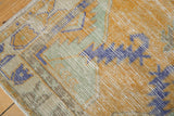 Detail of distressed Oushak rug showing worn pile, dusty gold, royal blue, seafoam green.