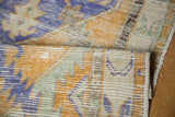 Close-up of distressed vintage Oushak rug pile, revealing faint foundation and soft colors.