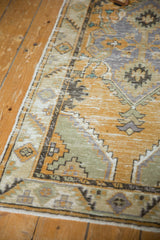 Distressed Oushak runner's worn pile texture with dusty gold, seafoam, and muted blue patterns.