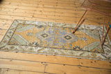 Distressed Oushak rug runner corner with faded gold, seafoam, and visible foundation.