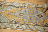 Distressed texture on a vintage Oushak rug, showing gold, grey, and seafoam green geometric motifs.