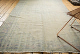 Faded beige and blue distressed vintage Oushak rug with worn pile and visible foundation.