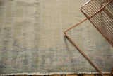 Distressed low pile and muted beige tones of a vintage Oushak rug with fringed edge.