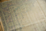 Distressed vintage Oushak carpet close-up showing worn pile, faded green, beige, and foundation.