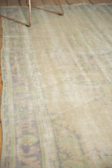 Textured beige distressed Oushak carpet pile with visible foundation and faded scrolling border.