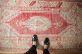 Distressed vintage Oushak rug: elongated medallion, arrow finials, blush cochineal, saffron, visible wear.