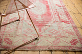 Distressed Turkish Oushak rug corner: pale cochineal red serrated leaf border, ivory tones.