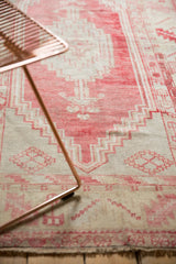 Distressed vintage Oushak rug texture, showing blush and ivory geometric stepped patterns.