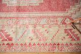 Distressed Oushak rug: low pile texture, blush serrated border, and ivory stepped motifs.