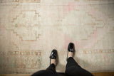 Vintage distressed Oushak rug's low pile, showing a stepped medallion and pale pink abrashed field.