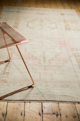 Distressed vintage Oushak rug's pale blush and faded bronze geometric motifs with soft low pile.