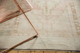 Distressed Oushak rug's low pile, geometric border in pale ivory, pink, and bronze.