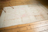 Distressed Oushak rug corner, with pale bronze geometric border and secured end fringe.
