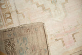Distressed Oushak rug's low pile with wear, showing its hand-knotted reverse.