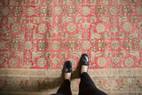 Feet on a distressed vintage Sivas carpet, highlighting faded blush Herati motif.
