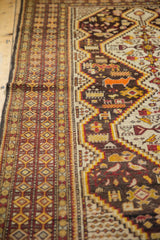 Vintage Caucasian rug with geometric diamond border, orange animal, cherry red, saffron yellow.