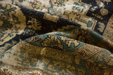 Folded Malayer rug fragment with navy, teal, beige palmette designs, storied texture, frayed edge.