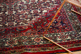 Hand-knotted: intricate Herati motif, stepped borders in cherry red, ivory, navy, and blush.