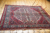 Detailed Herati motif in cherry red, ivory, and navy blue, with fringed edge.