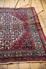 Secured ivory fringe and cherry red, navy, green patterned border of a Bibikabad carpet.