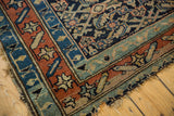 Antique Kurdish rug corner, displaying madder root red running border, navy field, and tattered edges.