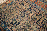 Close view of antique Kurdish rug's Herati motif, showing pile wear and tattered fringe.
