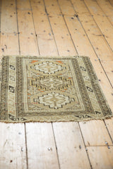 An antique Caucasian square rug with geometric guls and a serpent border, viewed from a high angle.