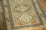 Angled view of the antique Caucasian rug's corner, showing the serpent border and secured end with short fringe.