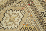 Hand-knotted detail of a geometric serpent border on an antique Caucasian rug in sand and ivory.