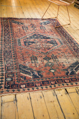 Worn fringe and geometric navy and brick red border on a vintage West Persian rug.