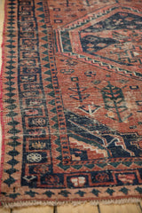 Hand-knotted West Persian rug's geometric navy blue and dusty teal border on a brick red field.