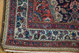 Tajabad rug corner: low pile, cherry red, navy, ivory floral borders, and white fringe.