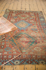 Antique Caucasian rug, geometric hook and latch motifs, pomegranate fills, red, sky blue, green, and worn pile.